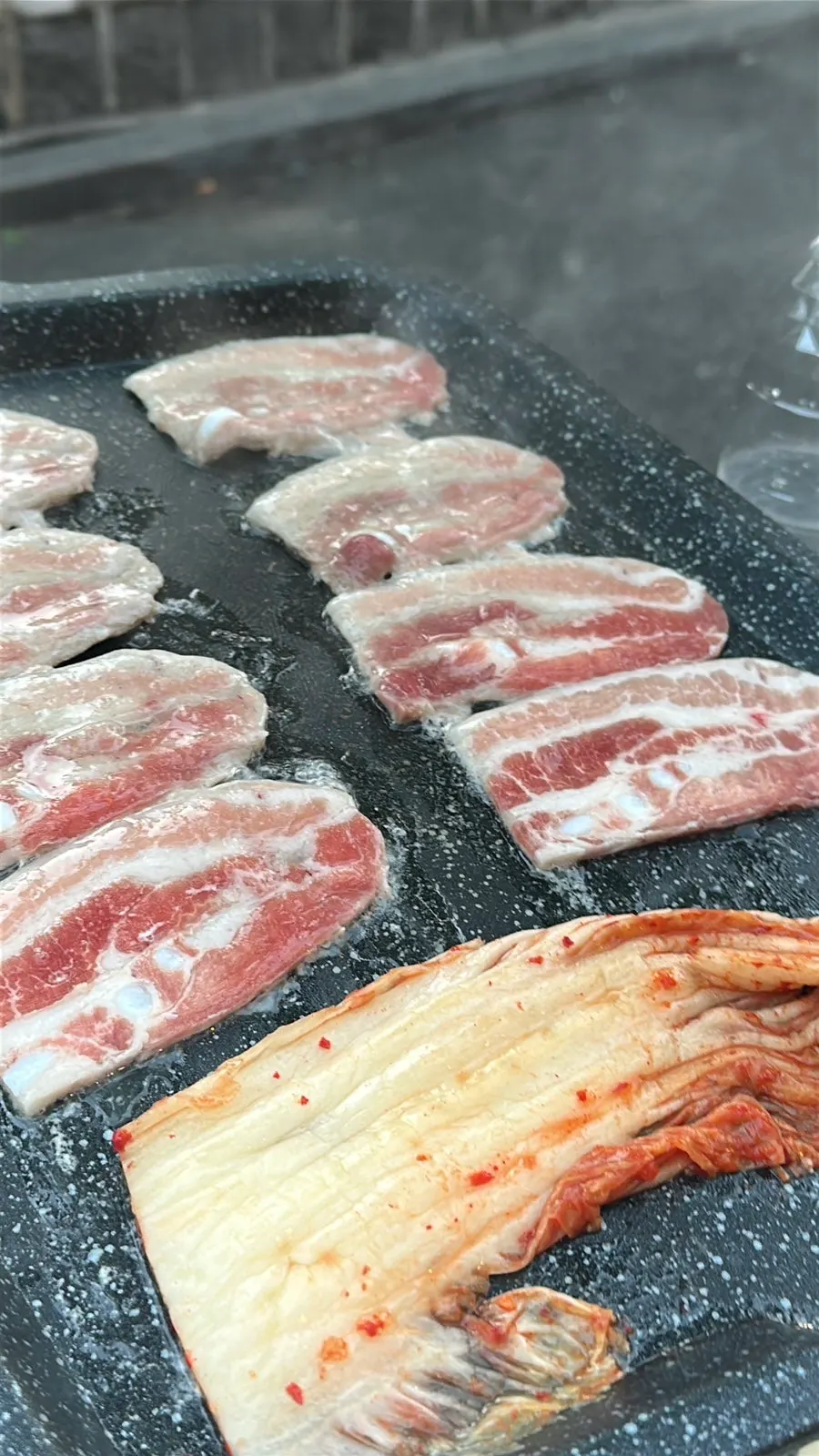 Frozen pork belly cooking on the outdoor grill