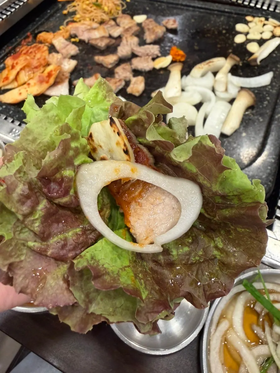 쌈채소에 올린 삼겹살 한 점