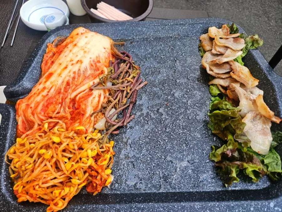Frozen pork belly and kimchi grilling on the pan