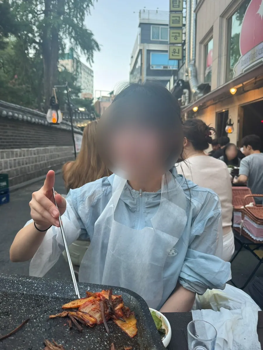 A piece of thin-cut pork belly topped with scallion kimchi