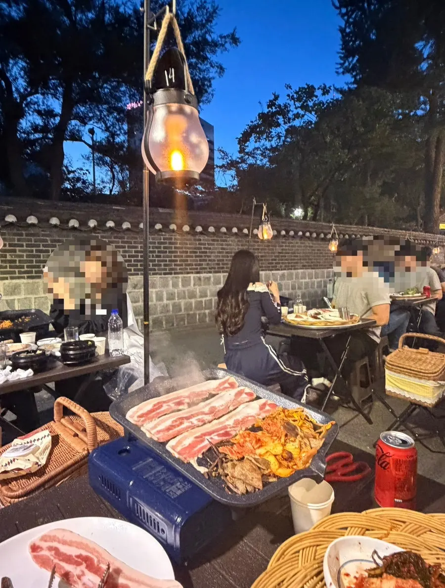 Outdoor meat-grilling table facing a stone wall