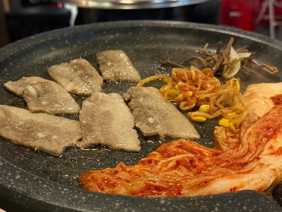 Frozen pork belly with kimchi, bracken fern and bean sprouts on the griddle