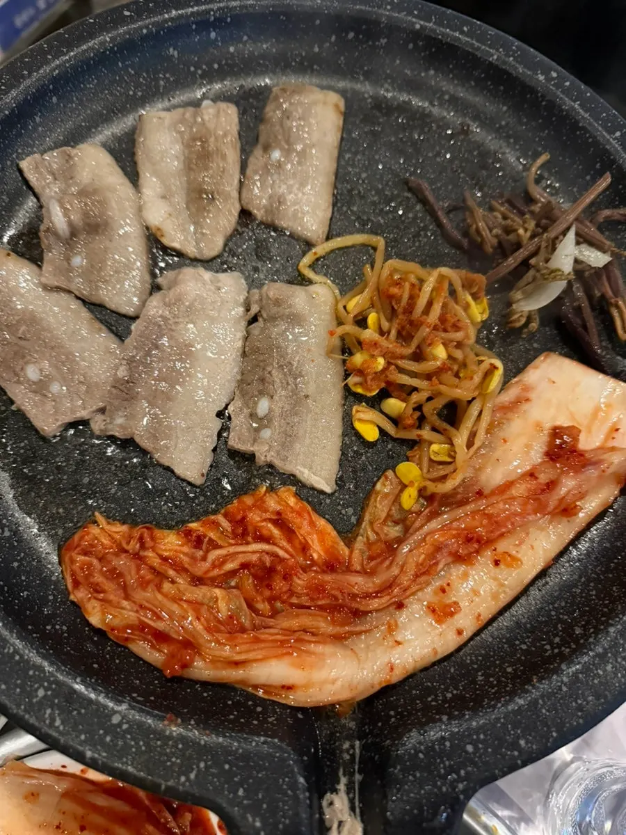 Bracken fern, bean sprouts and pork belly on the grill