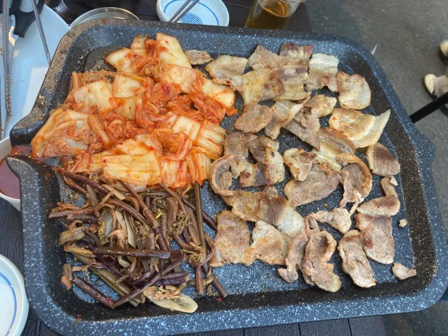 Outdoor grilled meat being seasoned with pepper