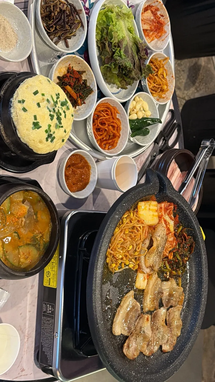 A full outdoor tent spread with meat, stew, and steamed egg
