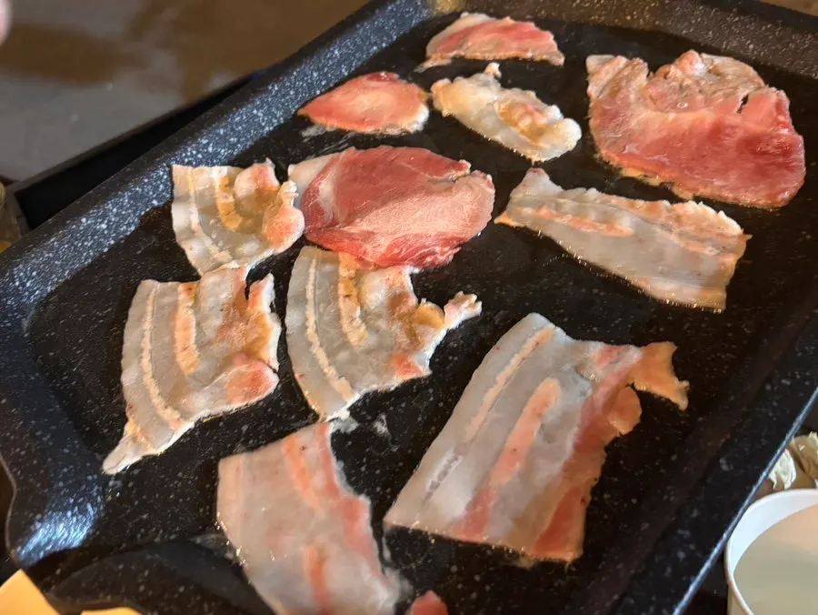 Frozen pork belly cooking on the grill