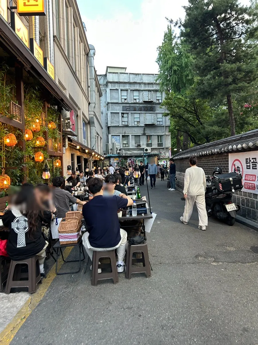 Outdoor tables in Jongno 3-ga lined along the stone wall beside Tapgol Park
