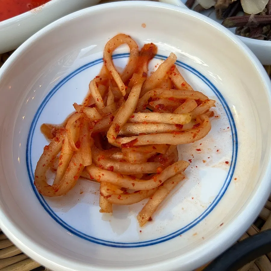 A basket beside the table with dining supplies