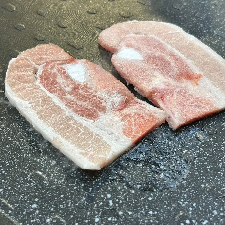 Two portions of thickly sliced flash-frozen pork belly