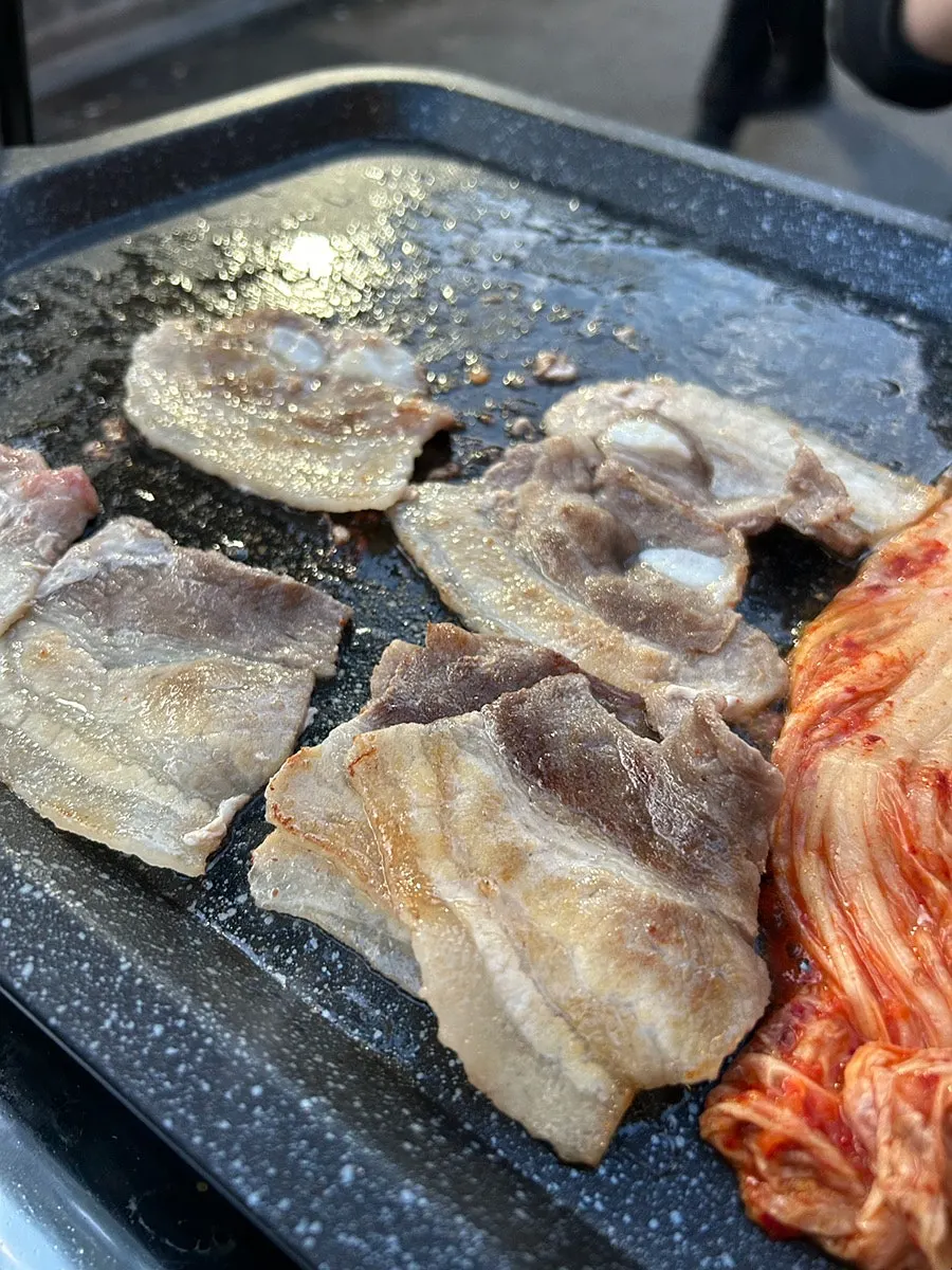 Pork belly enjoyed at an outdoor table beside the stone wall