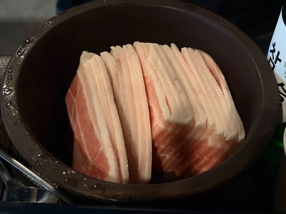 Frozen pork belly grilling on a stone plate