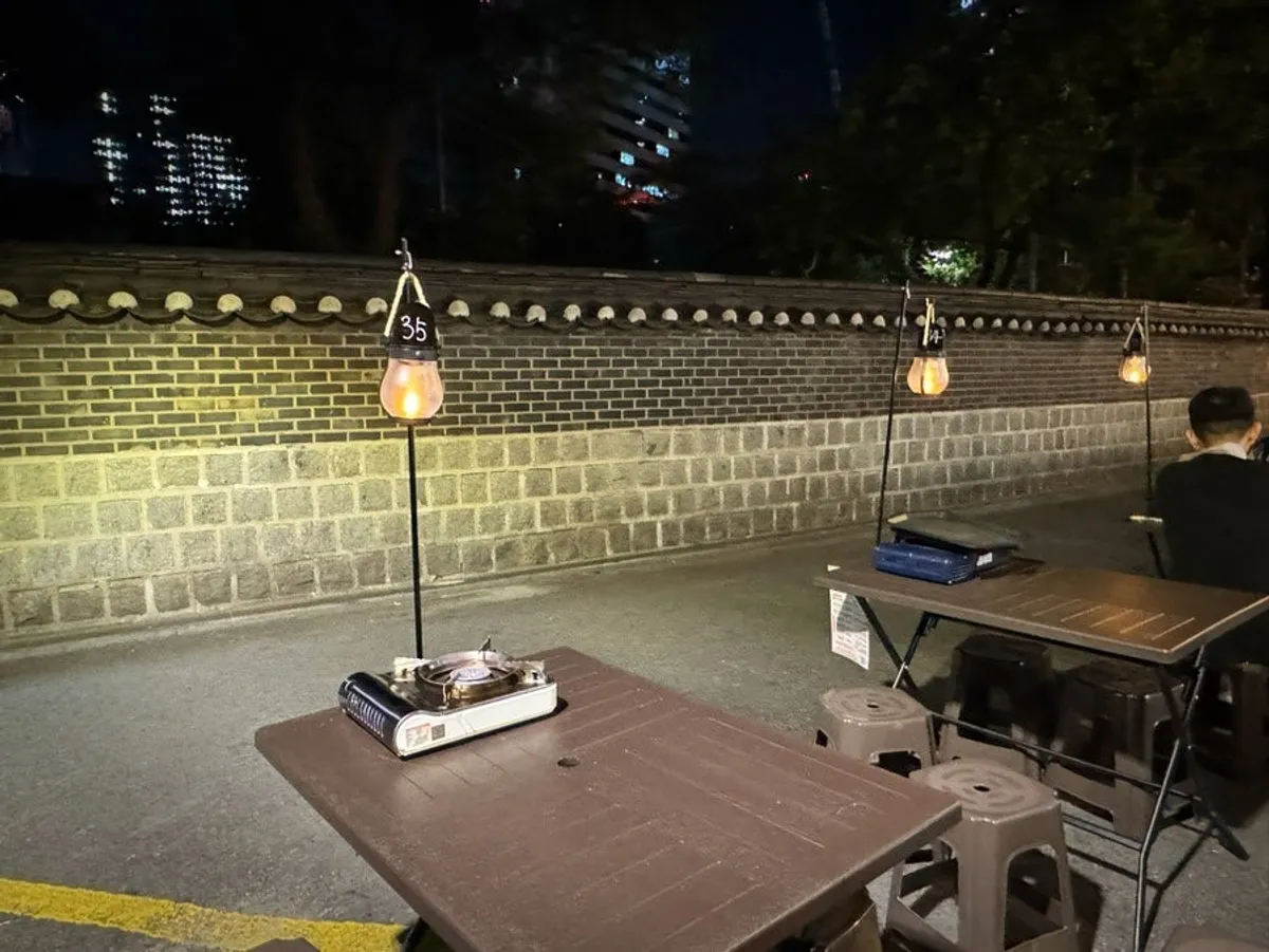 Outdoor tables and lantern lighting along the stone wall