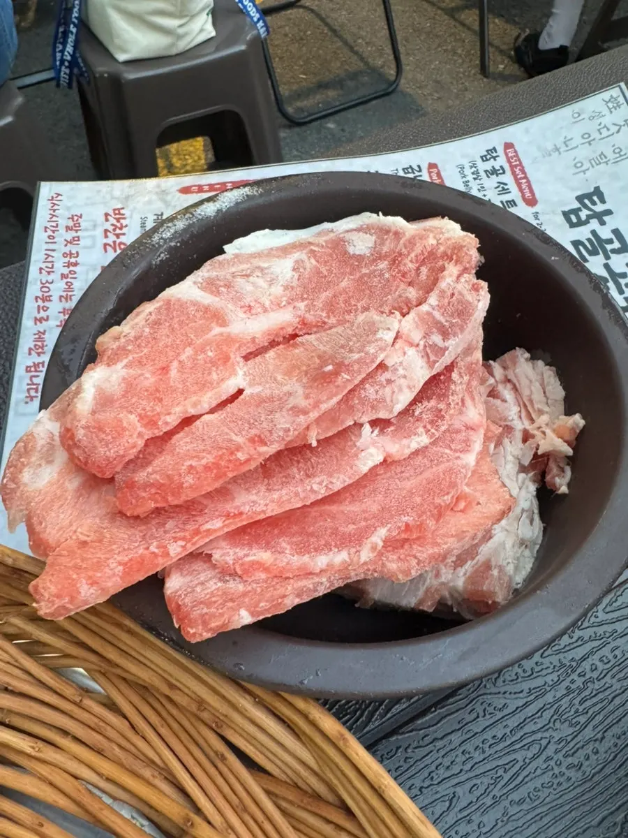 Flash-frozen pork belly and flower pork neck on a foil-lined grill