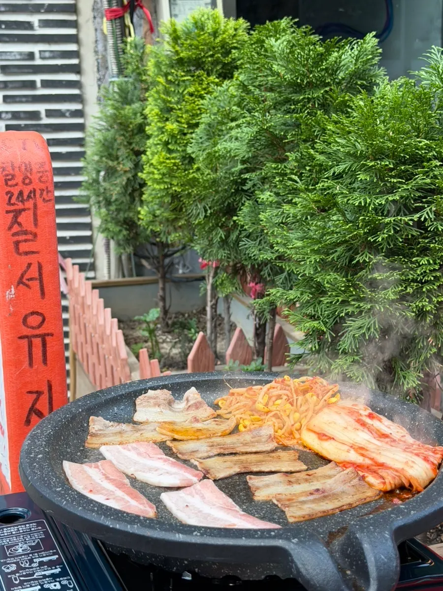Thin frozen pork belly cooking golden brown on the grill