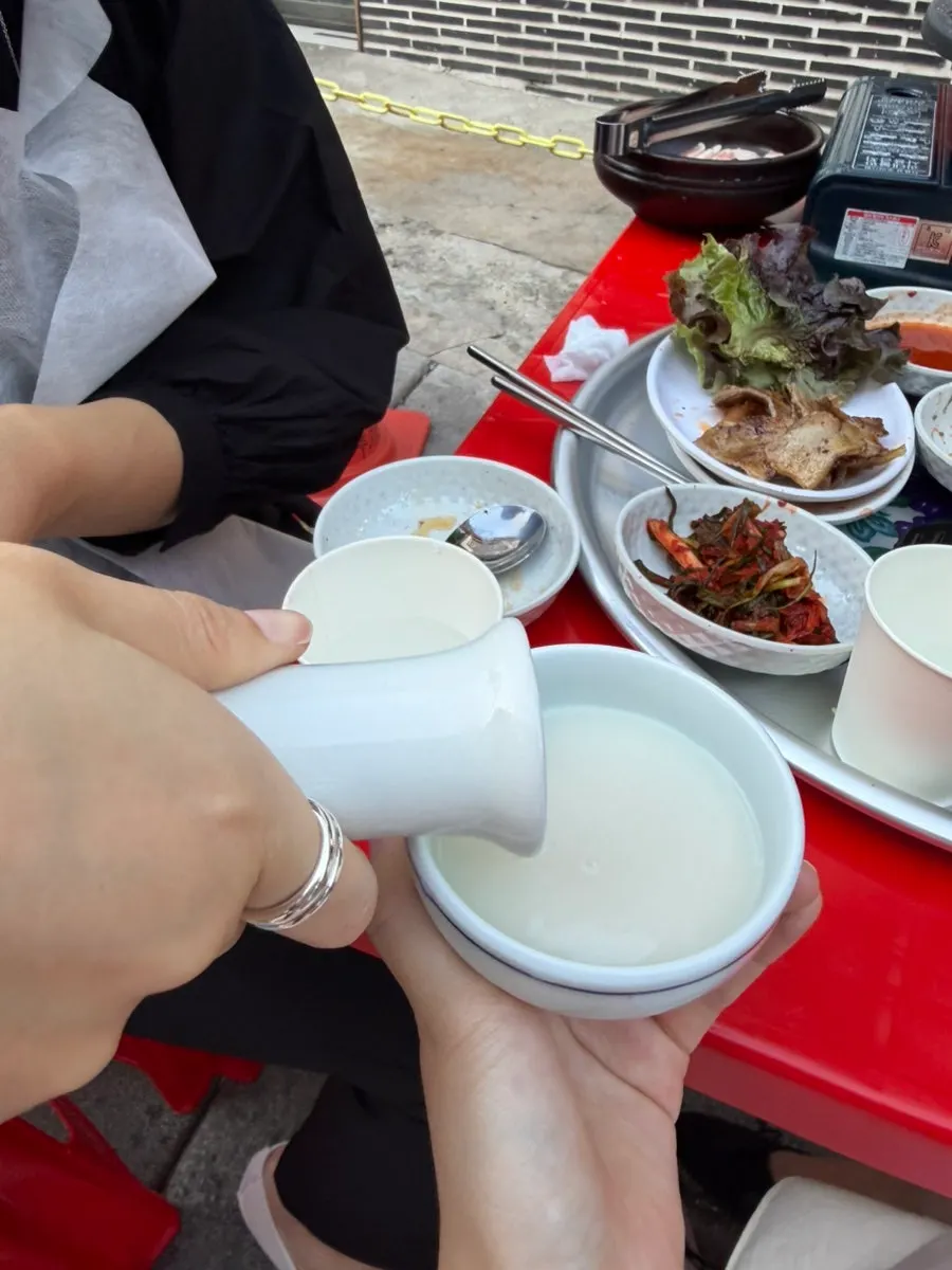A glass of makgeolli ordered alongside the pork belly