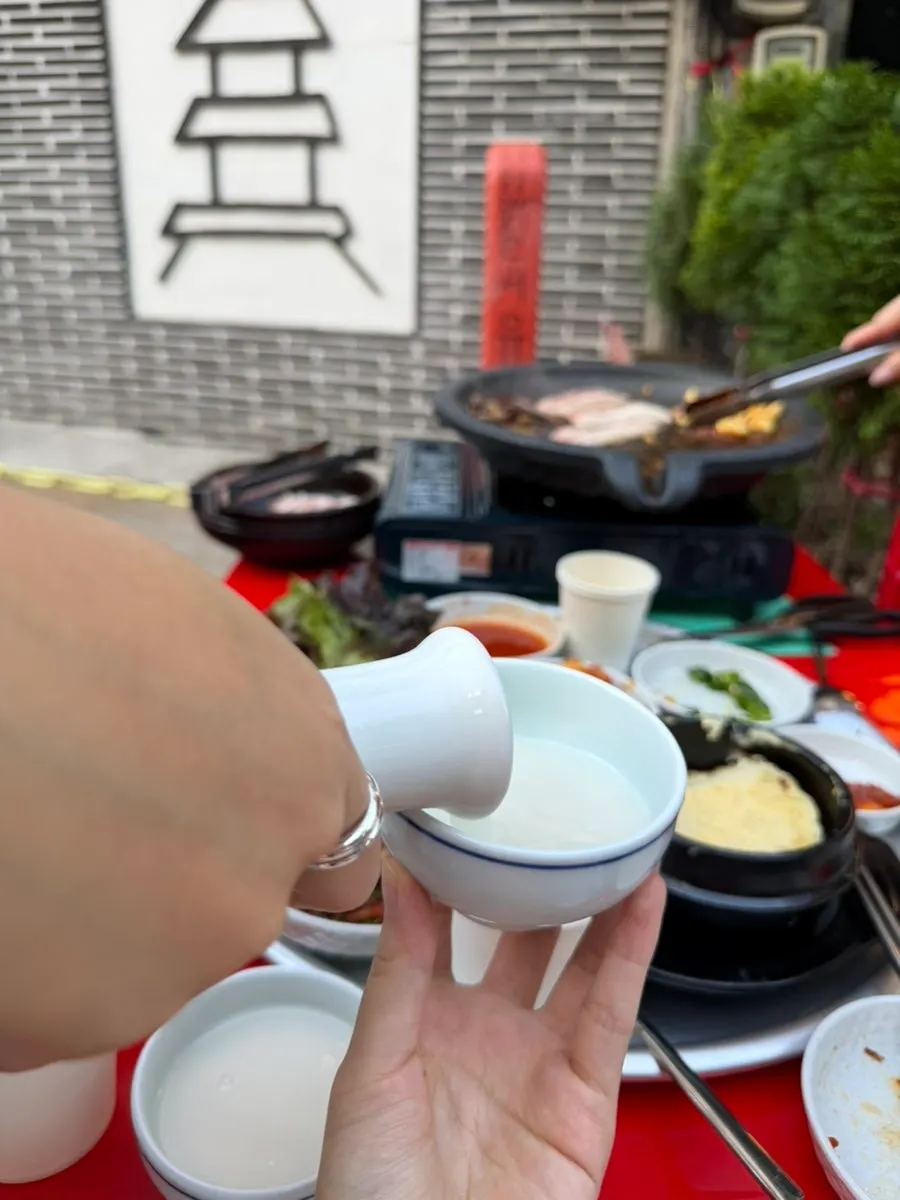 Makgeolli and meat set out on the outdoor table