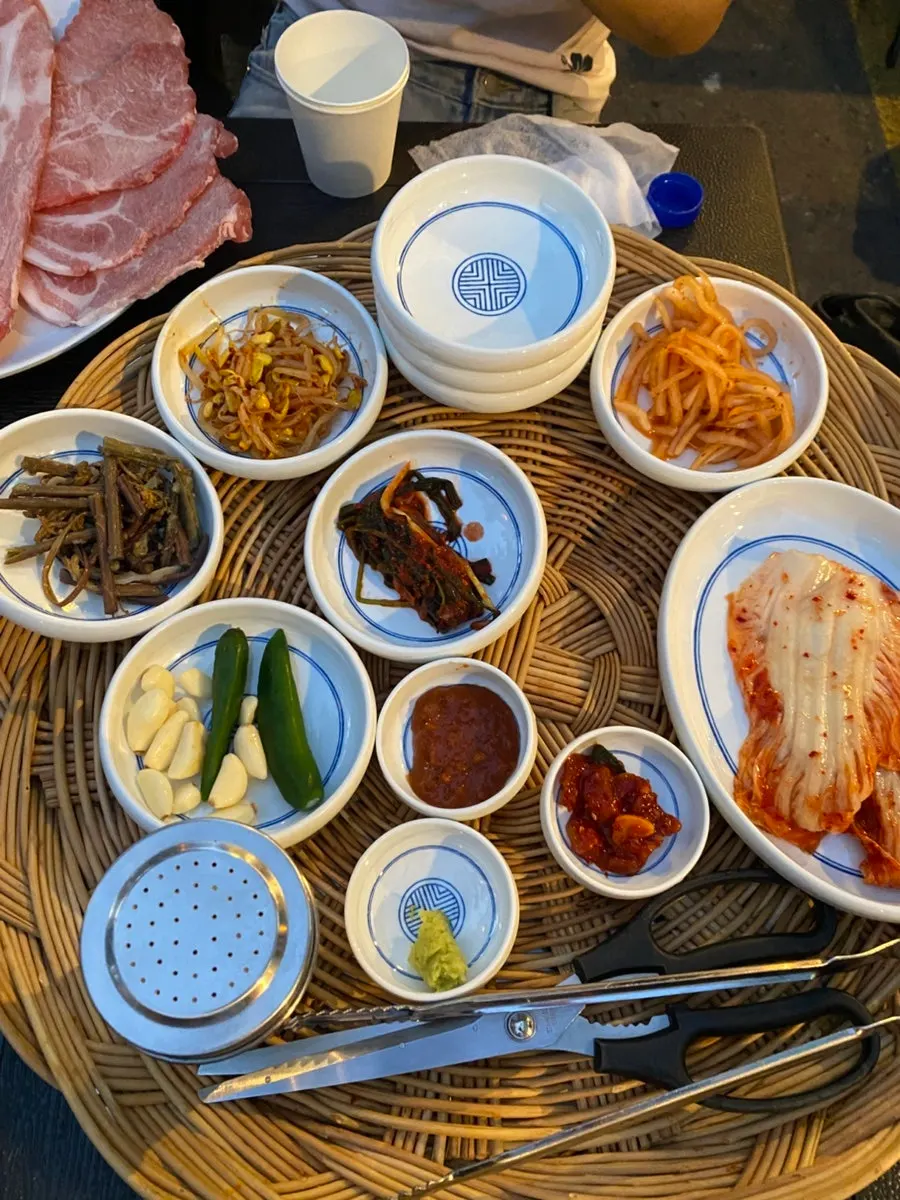 Picnic basket with utensils and glasses between outdoor tables