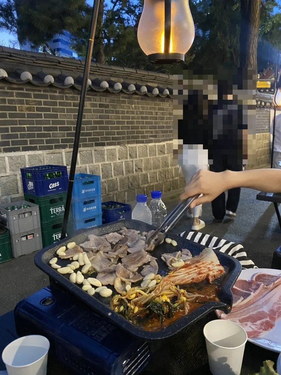 An atmospheric shot of the meat and soju at the outdoor table