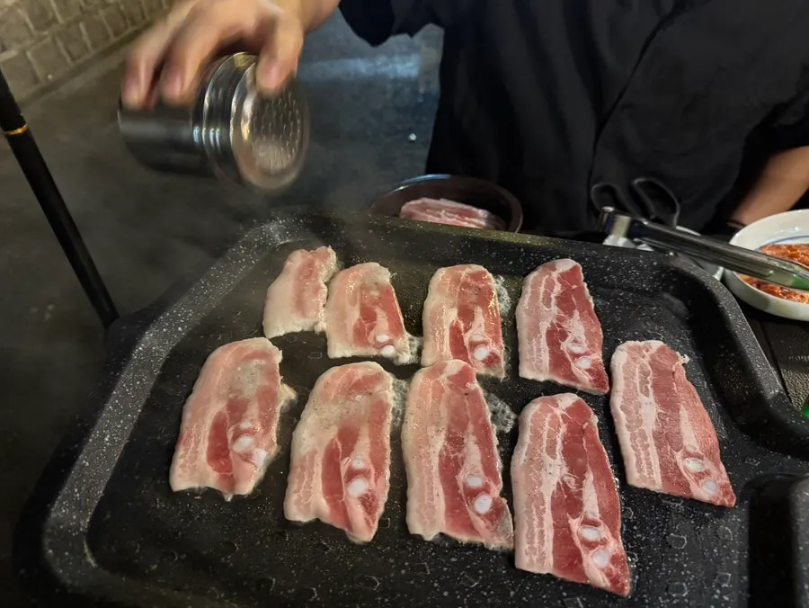 Frozen pork belly on the grill with pepper