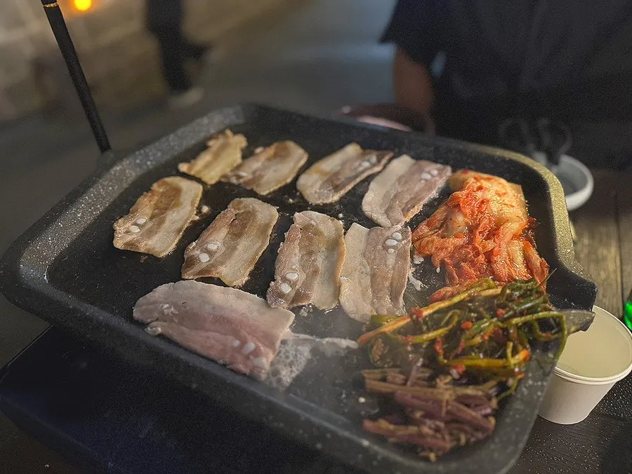 Pork belly and kimchi cooking together on the grill
