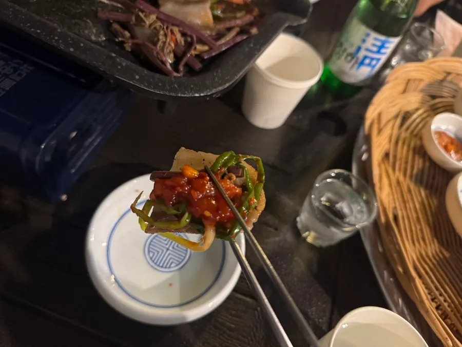 Grill with bracken fern and bean sprouts cooking alongside the meat