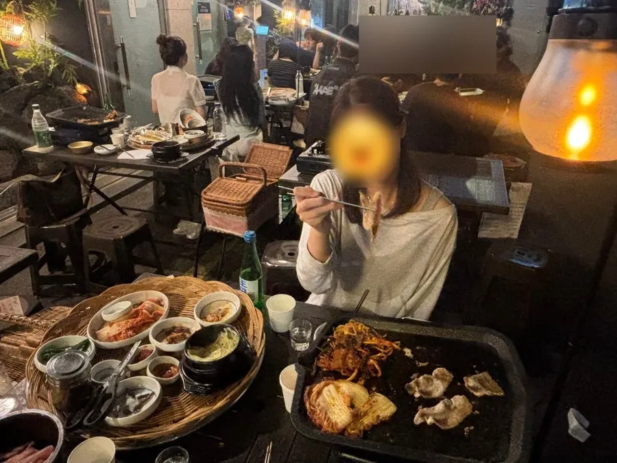Scene of people grilling meat outdoors on a cool evening