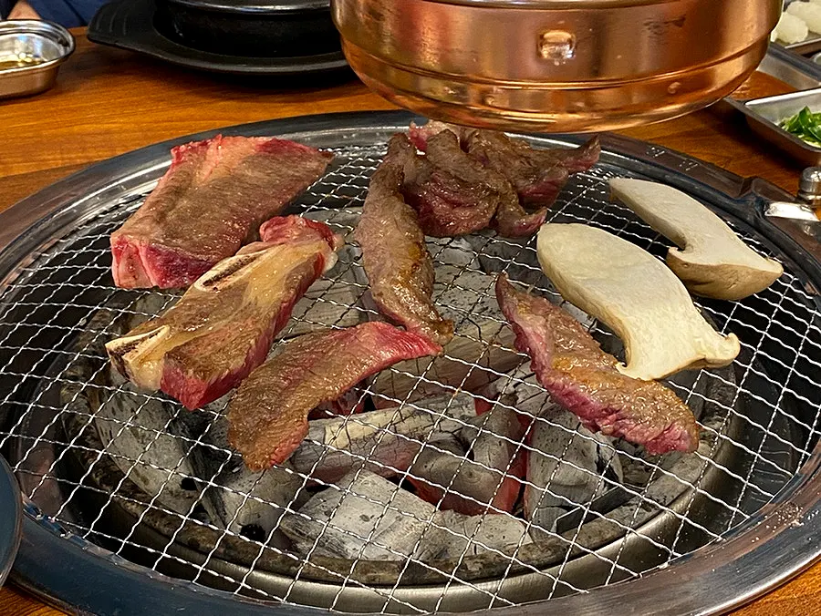 Beef grilling over a mild charcoal fire