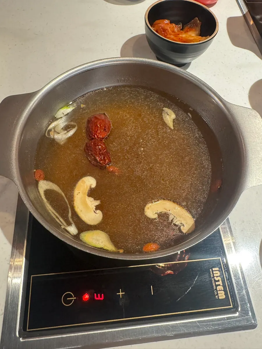 Individual pots of red broth and katsuo broth