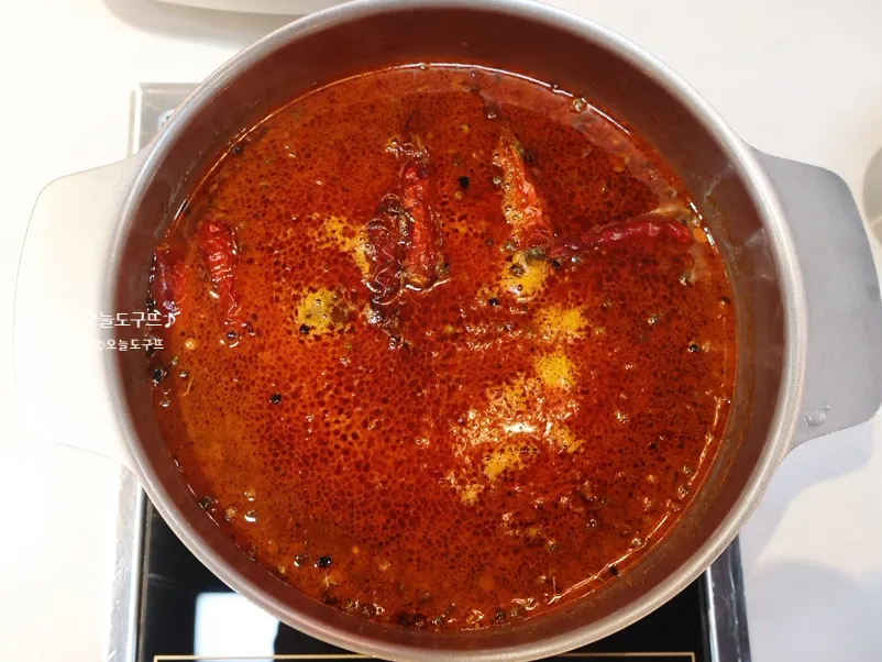 Personal pot of tom yum broth with lemongrass floating in it