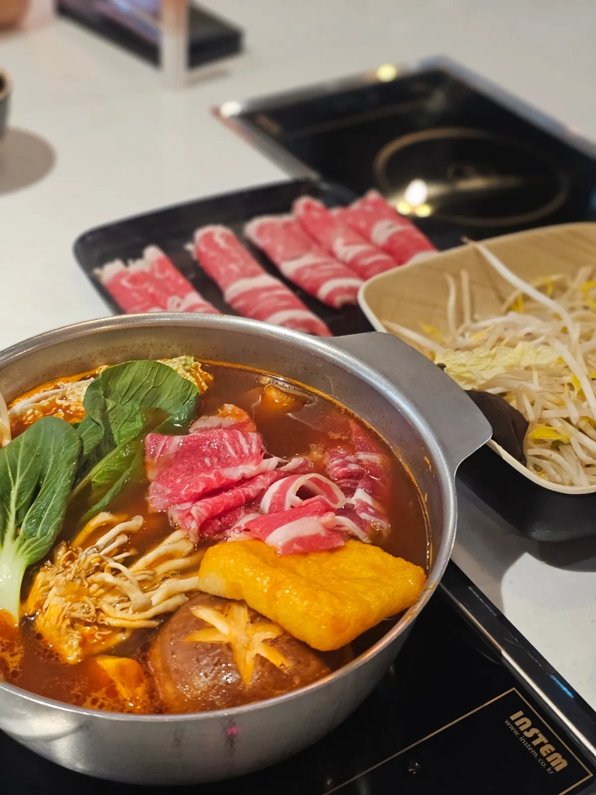 Tomato hot pot set with meat, glass noodles, vegetables, and shrimp balls