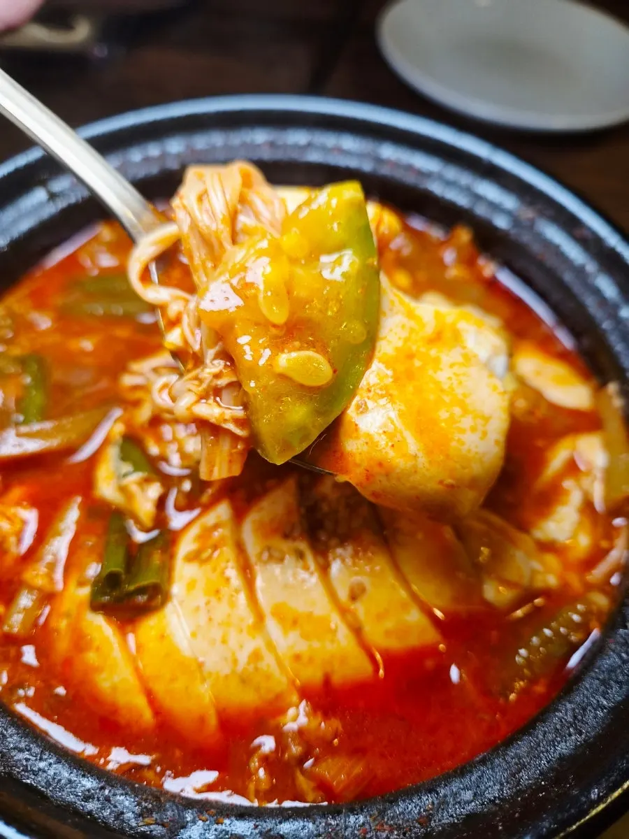 A spoonful of soft tofu stew broth