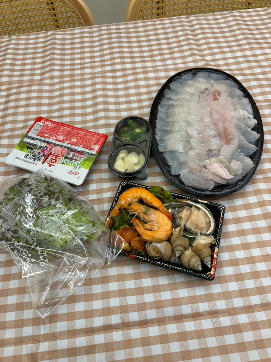 Sashimi, seafood, and wrapping greens laid out on the pension table