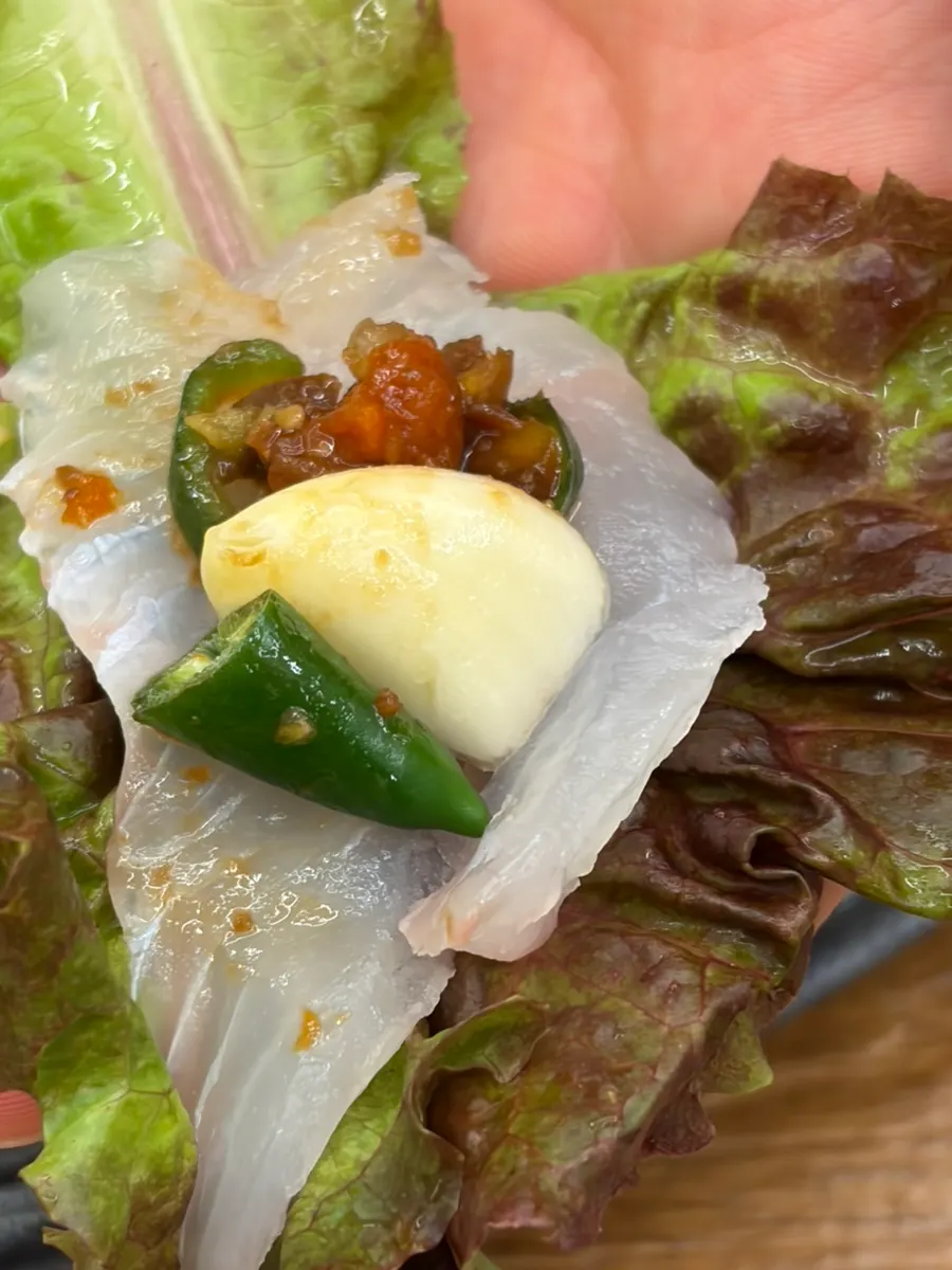 A thick piece of sashimi picked up with chopsticks