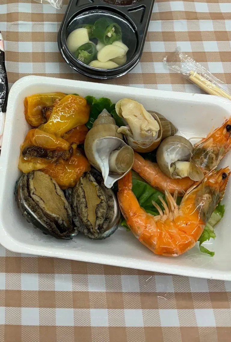 Sashimi takeaway packed with wrap greens, chojang, garlic, and chili peppers