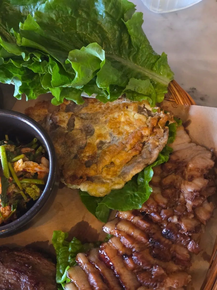 Bibimbap topped with seasoned vegetables and a fried egg, served with cold noodles