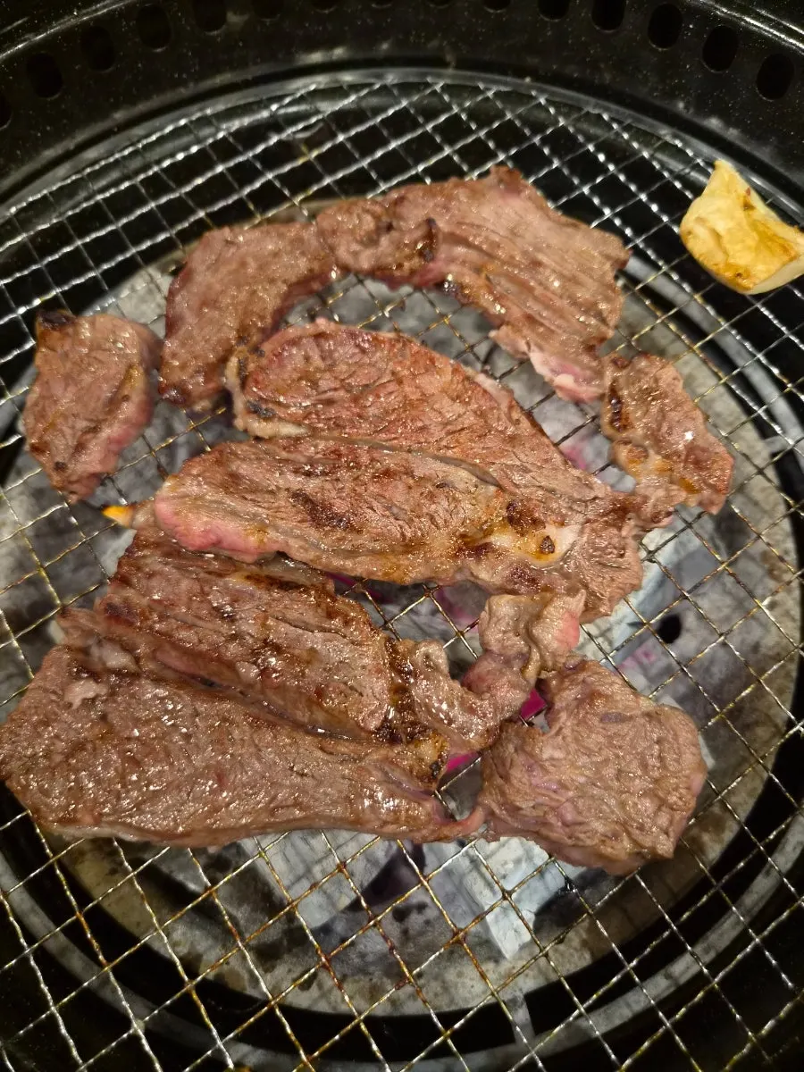 Beef grilling with mushrooms over charcoal