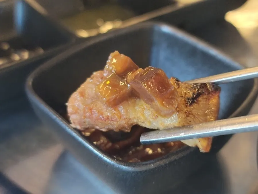 A piece of pork belly dipped in house sauce