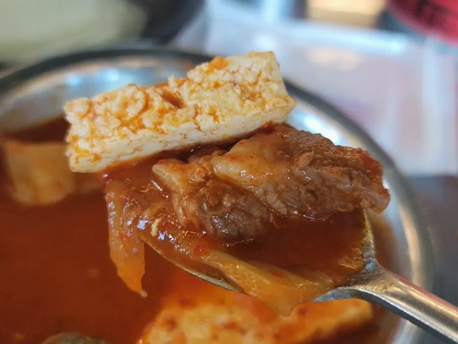 A bite of grilled pork belly topped with sour kimchi