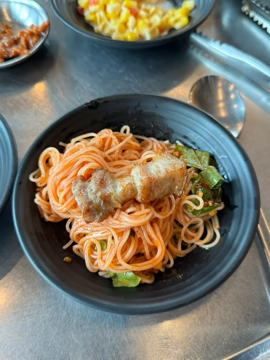 비빔국수 위에 올린 흑돼지 고기