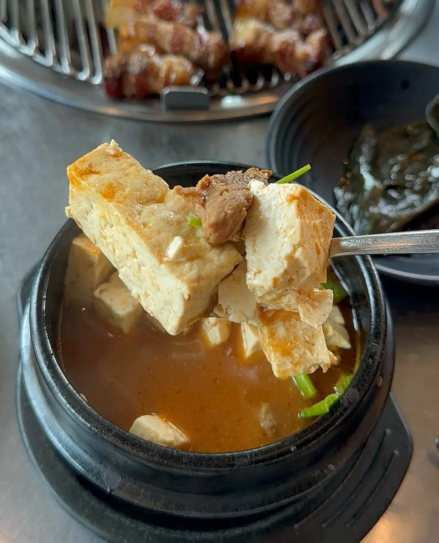 A bite of black pork with a bowl of rice