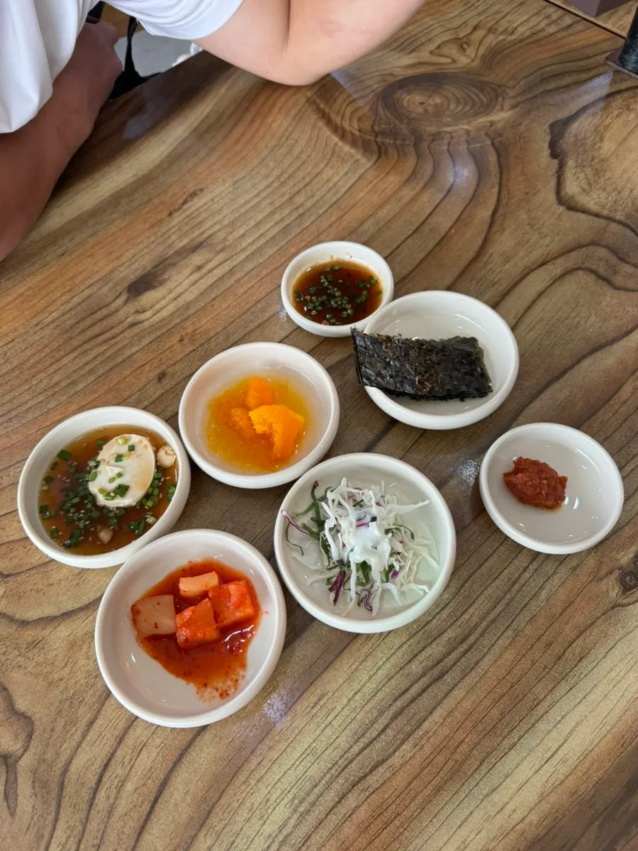 Standard side dish spread with diced radish kimchi, soft tofu sauce, salad, and seaweed