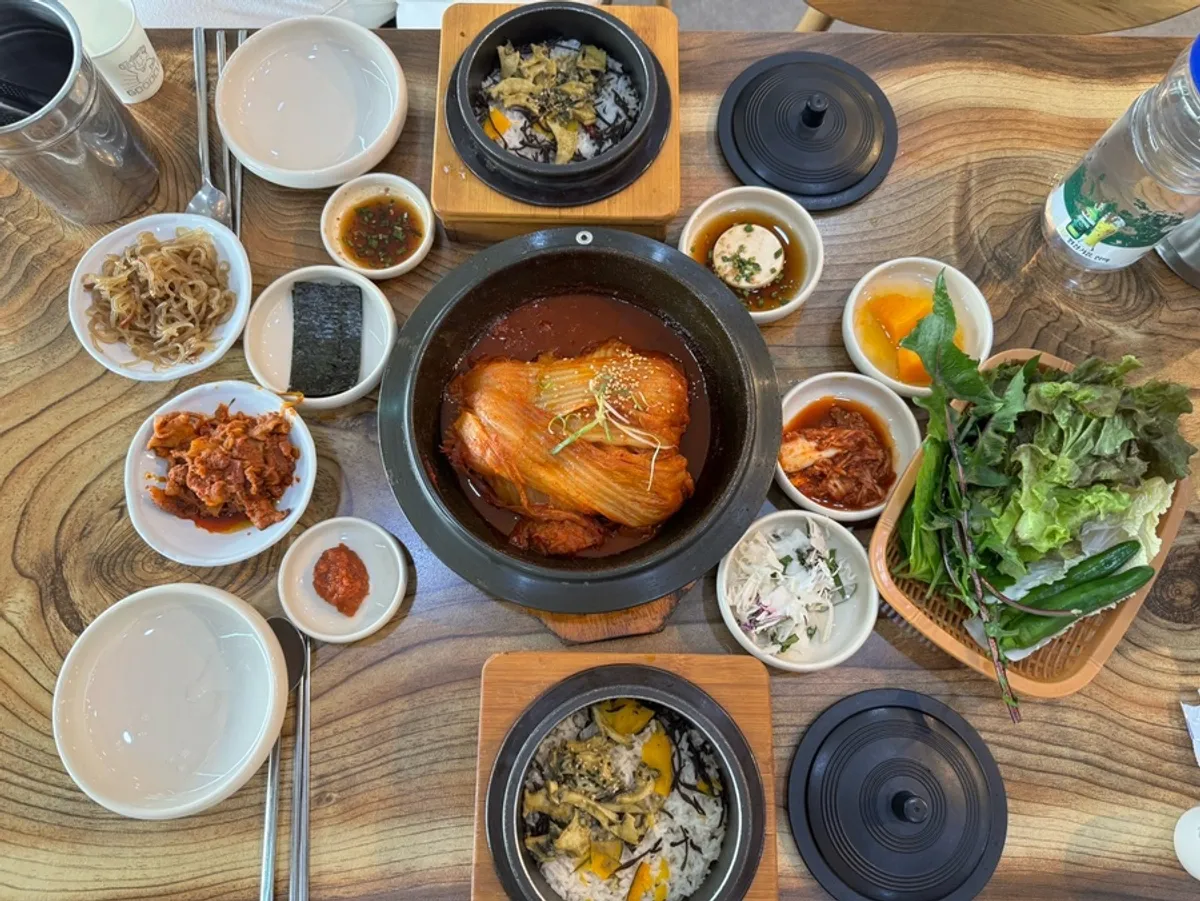 Full table spread of old kimchi mackerel ssam-bap and abalone hot stone rice