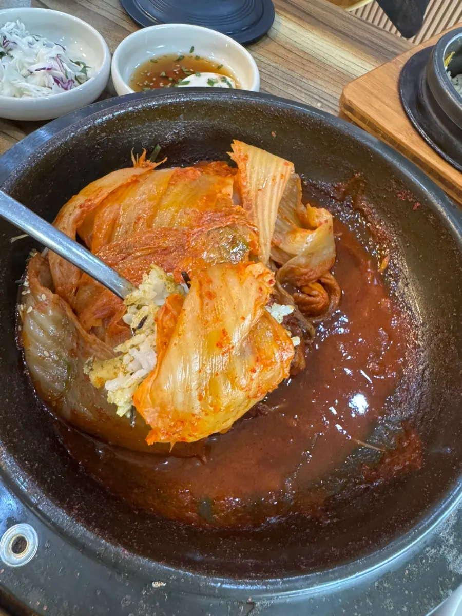 Old kimchi placed on top of a spoonful of abalone hot stone rice