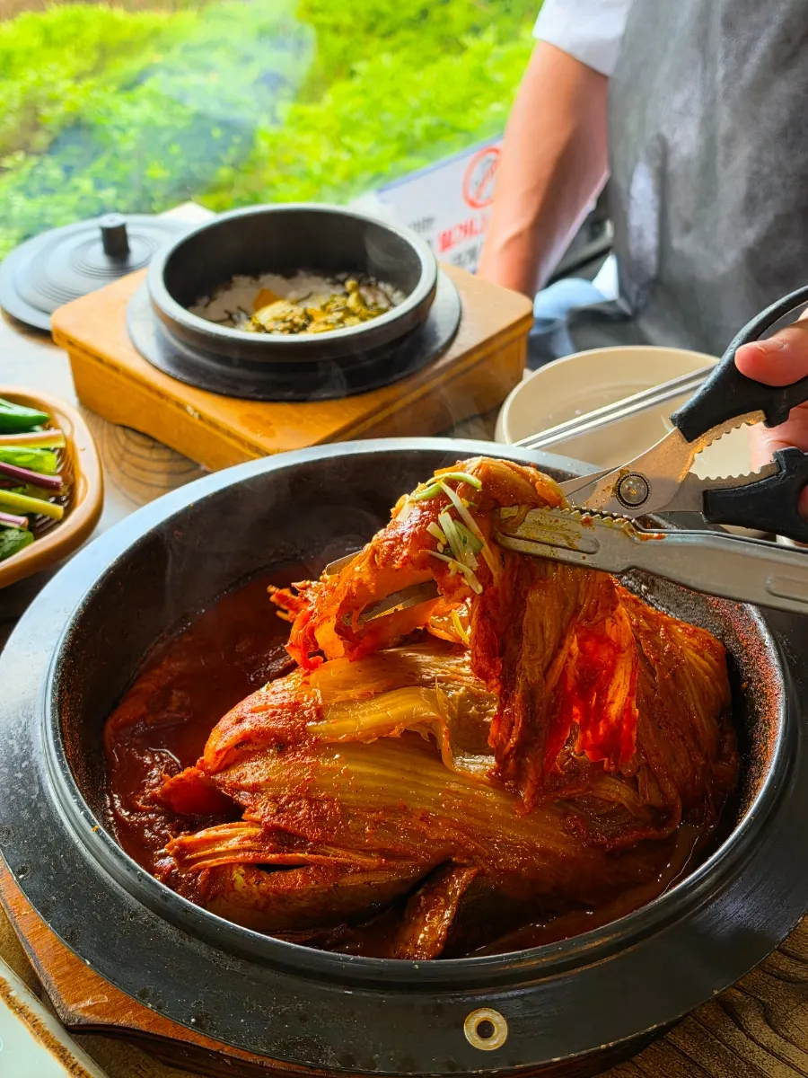 A piece of mackerel placed on top of old kimchi