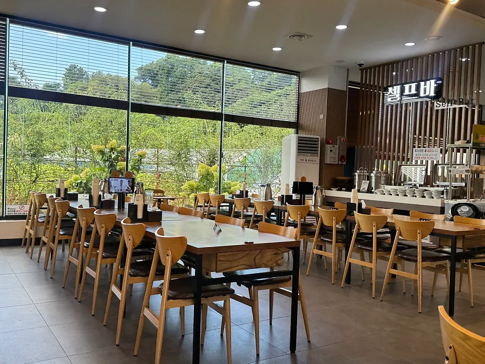 Spacious dining hall interior with garden view through floor-to-ceiling windows