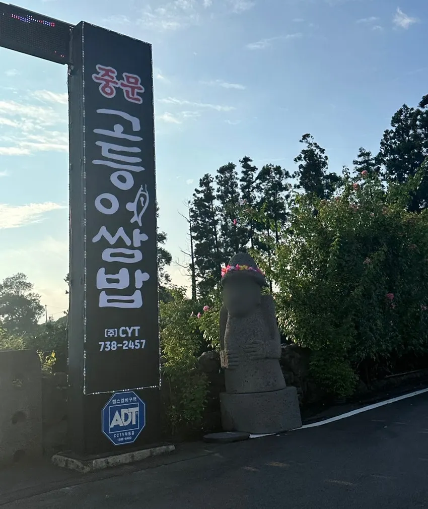 꽃 머리띠를 두른 입구의 큰 돌하르방