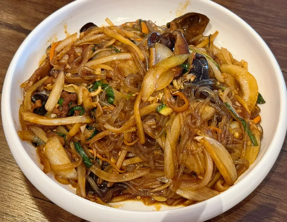 A bowl of japchaebap topped with glass noodle stir-fry