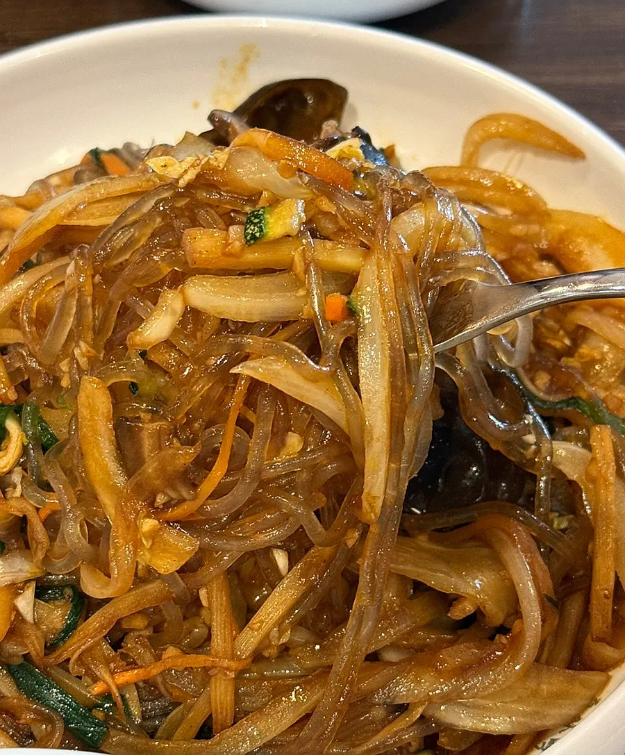 A spoonful of japchaebap lifted from the bowl