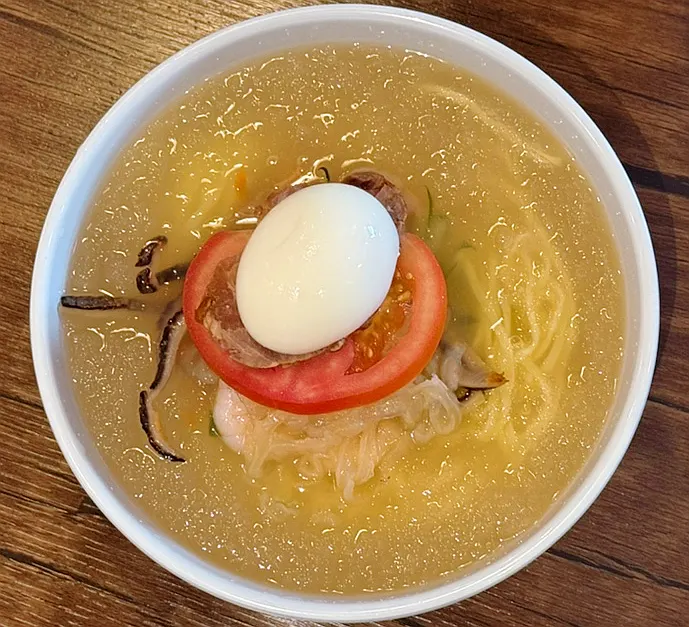 A bowl of jungwa naengmyeon with shaved ice floating on top