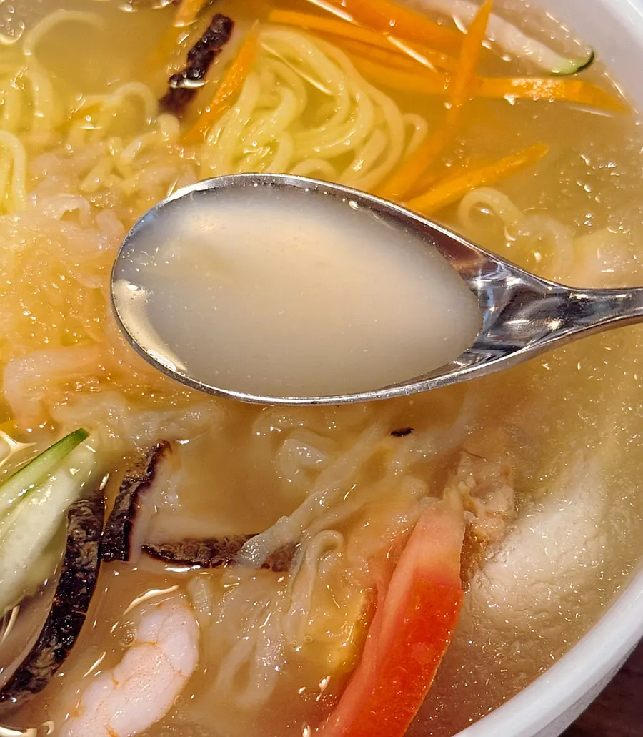 Close-up of the broth and vegetable toppings on jungwa naengmyeon